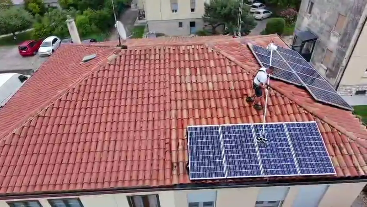 Un tetto in coppi visto dal drone, con i pannelli fotovoltaici e la persona che lavora